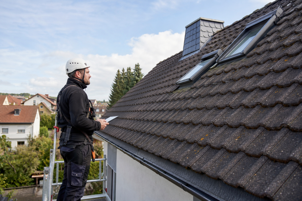 Techniker prüft ein Wohnhausdach für die Planung einer Photovoltaikanlage.